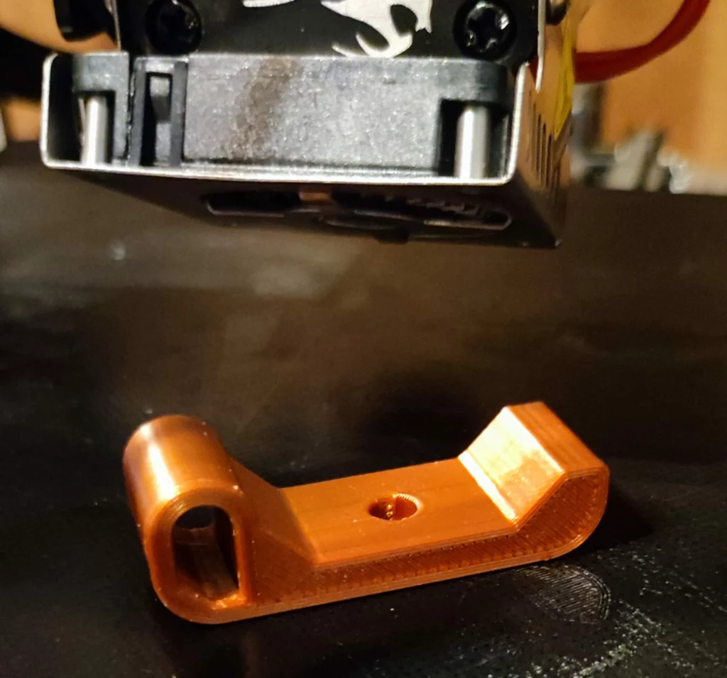 Bride mécanique imprimée en 3D, sous la buse de l'imprimante